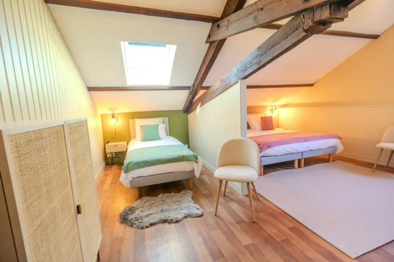 Chambre spacieuse sous les combles avec poutres apparentes, lit double et ambiance chaleureuse