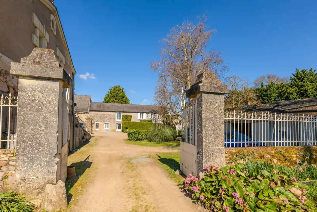 Entrée du château de Bois Brinçon avec portail en pierre et allée menant à la bâtisse principale