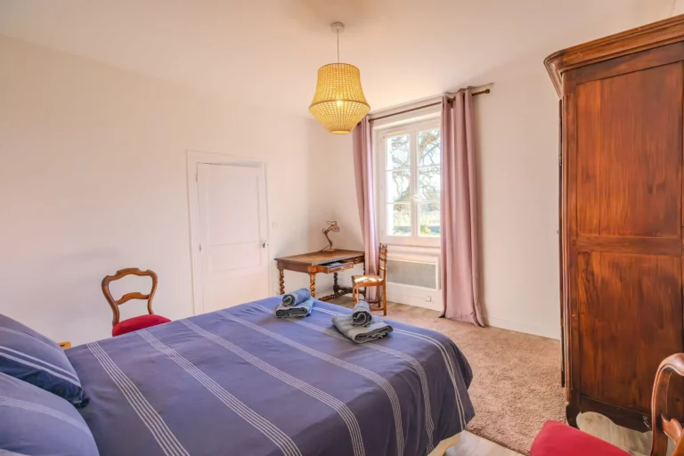 Chambre cosy à la Closerie avec lit double, armoire en bois et lumière naturelle
