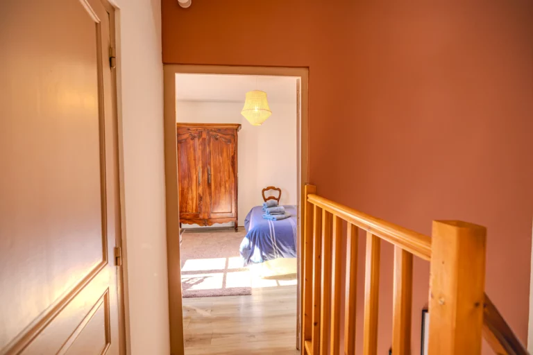 Couloir à l’étage menant à la chambre La Closerie avec armoire en bois visible au fond