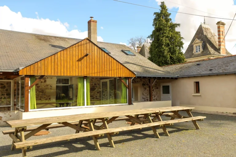 Façade en pierre des Demeures de Bois Brinçon avec grande table en bois pour repas en extérieur