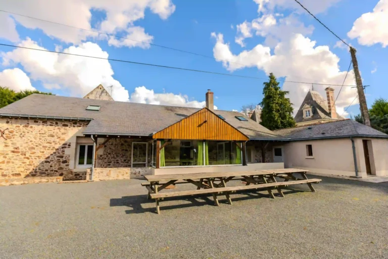 Façade en pierre des Demeures de Bois Brinçon avec grande table en bois pour repas en extérieur
